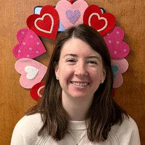 Hayley Lyon – February Employee of the Month | Oriol Health Care Hayley Lyon, HR and Finance Coordinator at Oriol Health Care, smiling while holding a branded Oriol Health Care mug in a hallway setting.